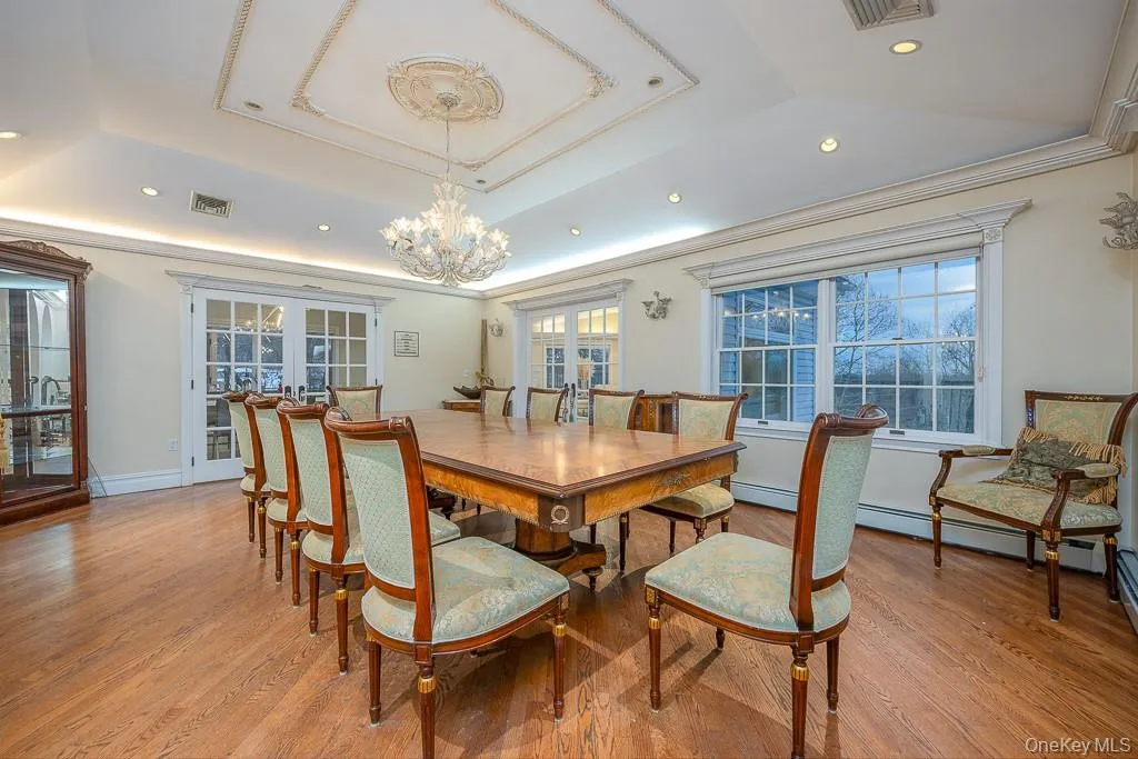 Dining room with french doors, light wood-style floors, a tray ceiling, recessed lighting, and ornamental molding Dining room with french doors, light wood-style floors, a tray ceiling, recessed lighting, and ornamental molding