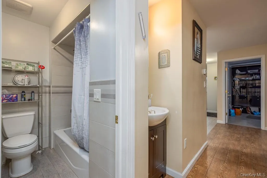 Bathroom with light wood-type flooring, vanity, shower / tub combo, and a walk in closet Bathroom with light wood-type flooring, vanity, shower / tub combo, and a walk in closet