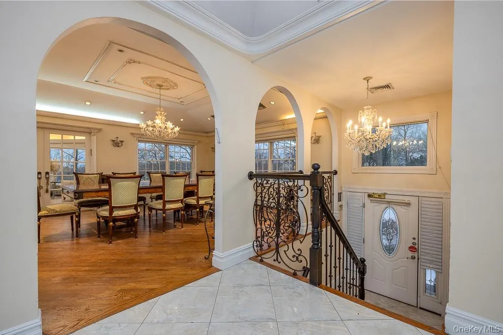 Tiled entryway featuring a chandelier, arched walkways, ornamental molding, and plenty of natural light Tiled entryway featuring a chandelier, arched walkways, ornamental molding, and plenty of natural light