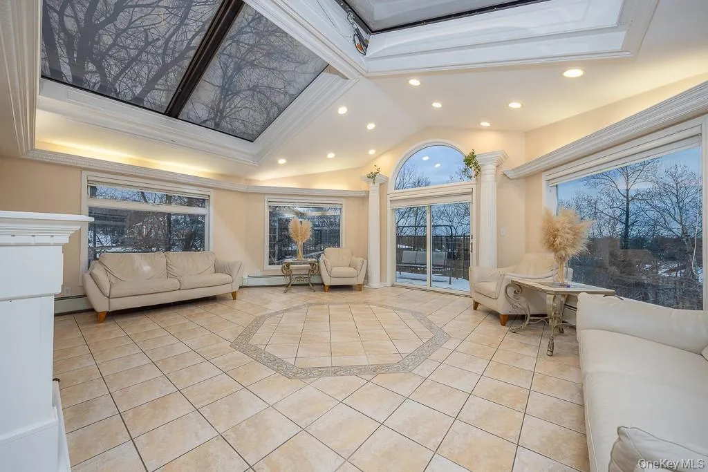 Living area featuring vaulted ceiling, inlaid floor details, light tile patterned flooring, a raised ceiling, and ornamental molding Living area featuring vaulted ceiling, inlaid floor details, light tile patterned flooring, a raised ceiling, and ornamental molding
