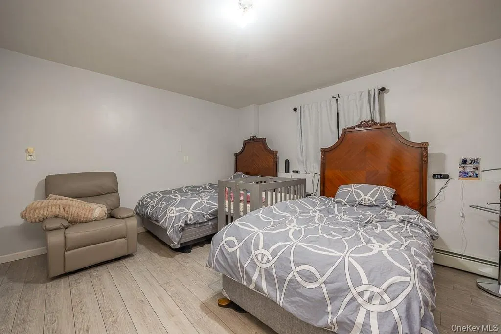 Bedroom featuring hardwood / wood-style flooring and a baseboard heating unit Bedroom featuring hardwood / wood-style flooring and a baseboard heating unit