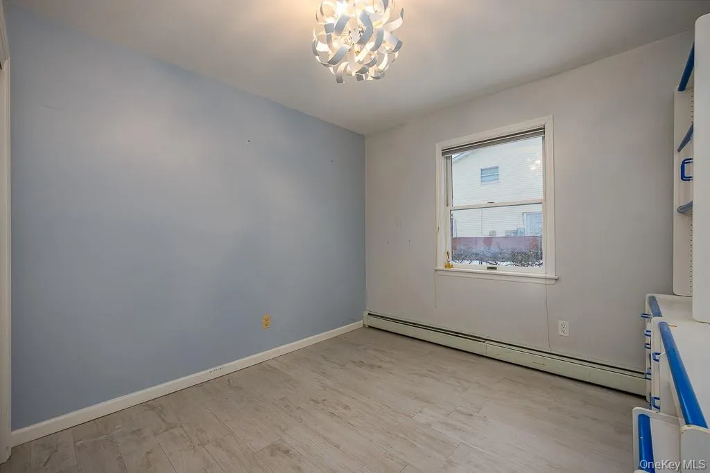 Unfurnished room featuring a baseboard heating unit, light wood-type flooring, and a chandelier Unfurnished room featuring a baseboard heating unit, light wood-type flooring, and a chandelier