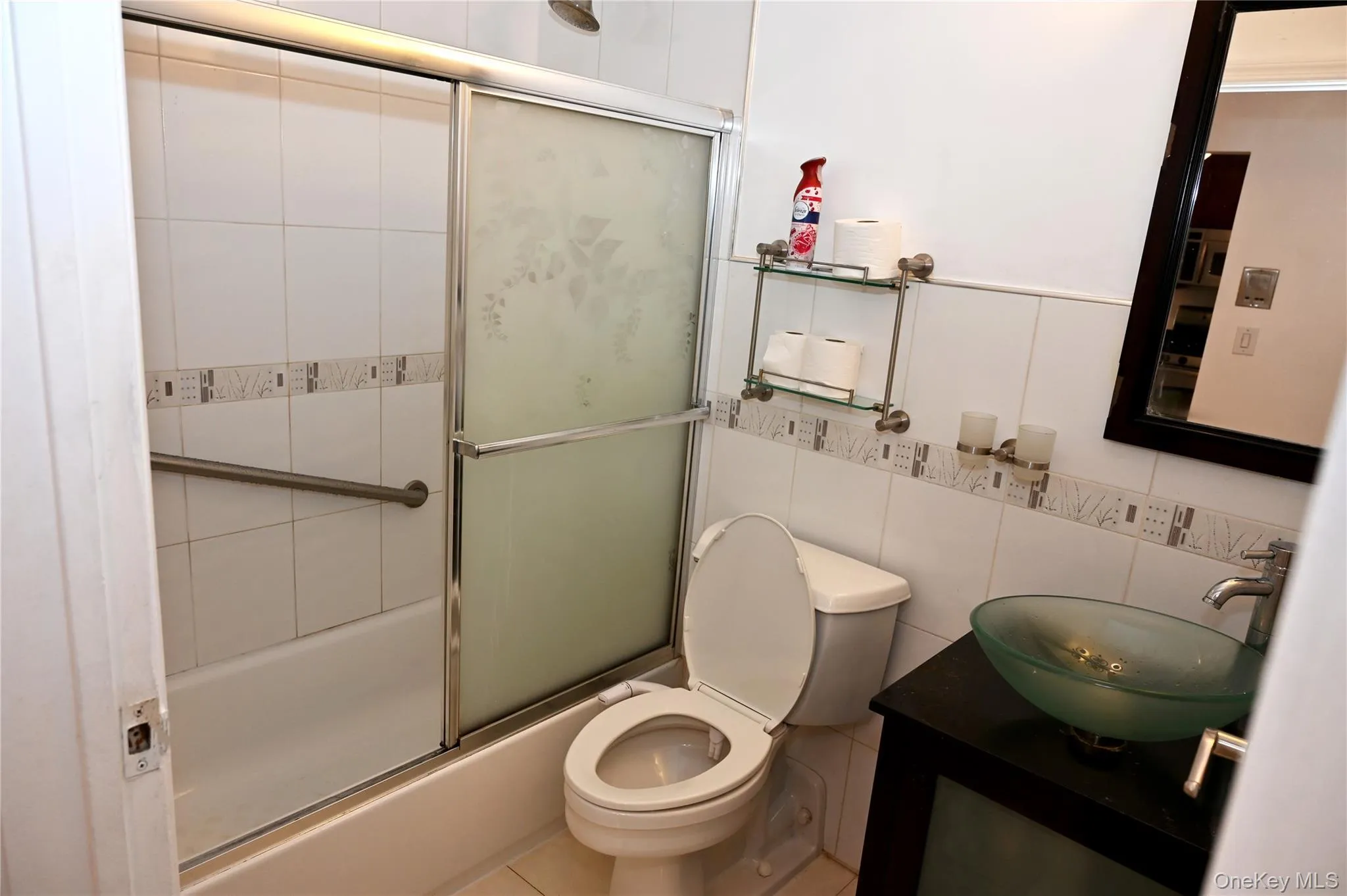 Bathroom featuring a glass vessel sink, dark wood-finish vanity, and a shower-tub combination with sliding frosted glass doors Bathroom featuring a glass vessel sink, dark wood-finish vanity, and a shower-tub combination with sliding frosted glass doors