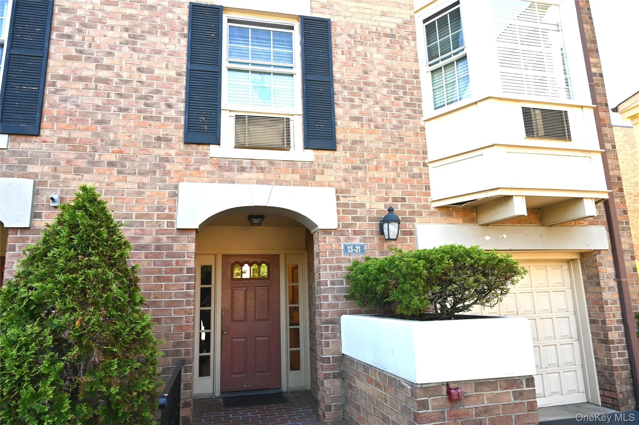 Brick facade featuring an arched entryway, decorative front door with transom and sidelights, an overhead sconce, and a bay window Brick facade featuring an arched entryway, decorative front door with transom and sidelights, an overhead sconce, and a bay window