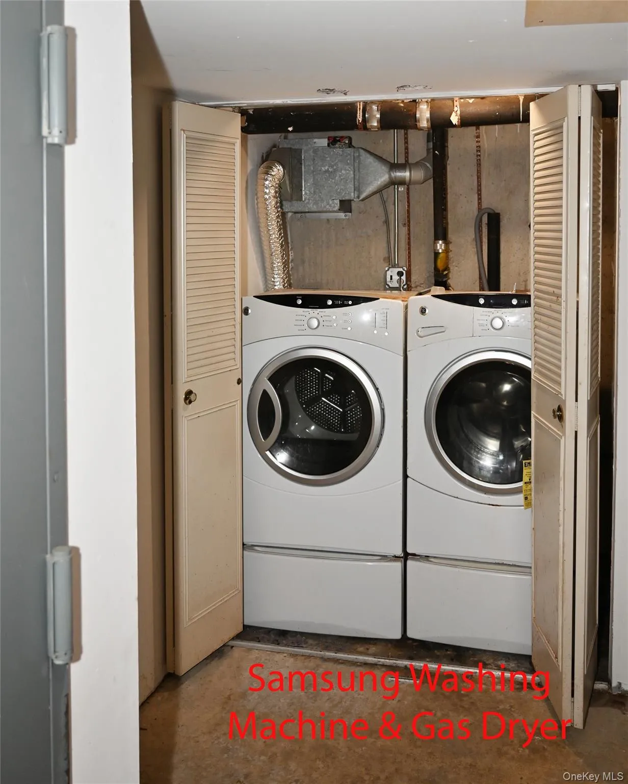Dedicated laundry area featuring a front-loading Samsung washing machine and gas dryer, concealed by louvered bi-fold doors Dedicated laundry area featuring a front-loading Samsung washing machine and gas dryer, concealed by louvered bi-fold doors