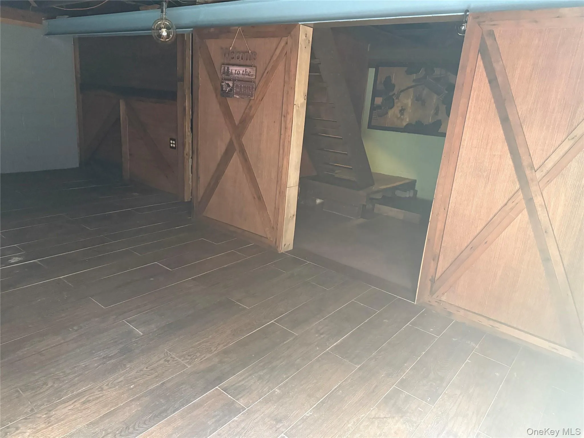 Below grade area featuring a barn door and dark wood-style flooring Below grade area featuring a barn door and dark wood-style flooring