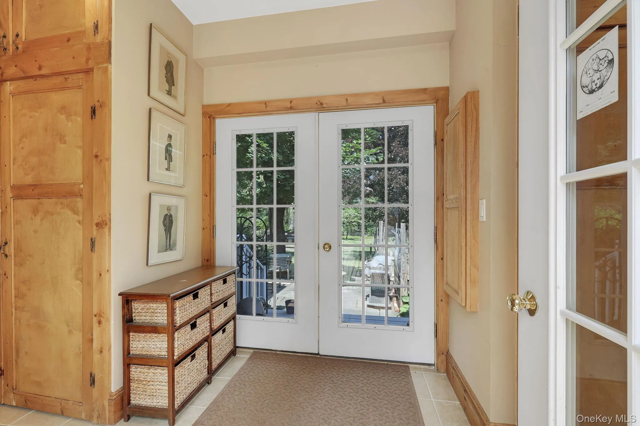 Entryway with double French doors with light wood trim, and neutral wall tones. Entryway with double French doors with light wood trim, and neutral wall tones.