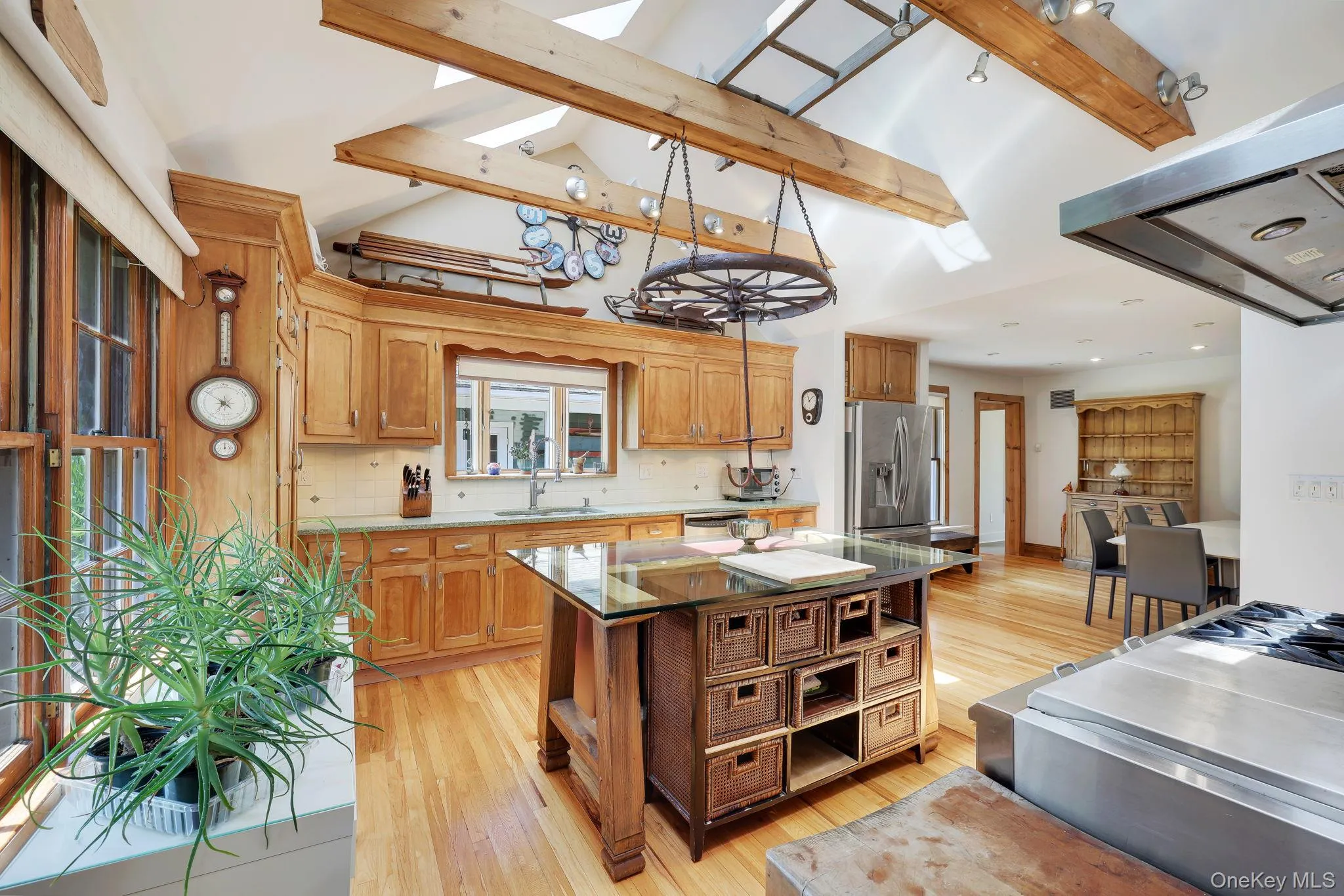 Kitchen with natural wood cabinetry, stainless steel appliances, hard wood flooring, wooden beams and skylights. Kitchen with natural wood cabinetry, stainless steel appliances, hard wood flooring, wooden beams and skylights.