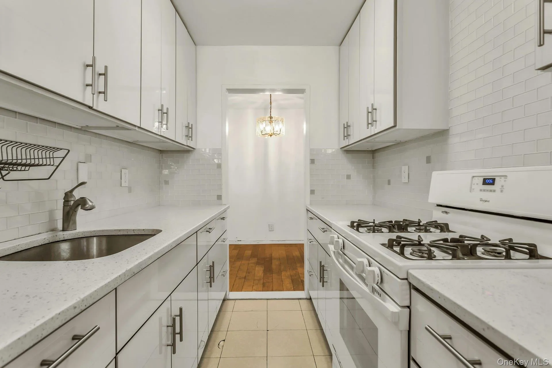 Kitchen with white gas range oven, light stone countertops, light tile patterned floors, white cabinetry, and a chandelier Kitchen with white gas range oven, light stone countertops, light tile patterned floors, white cabinetry, and a chandelier
