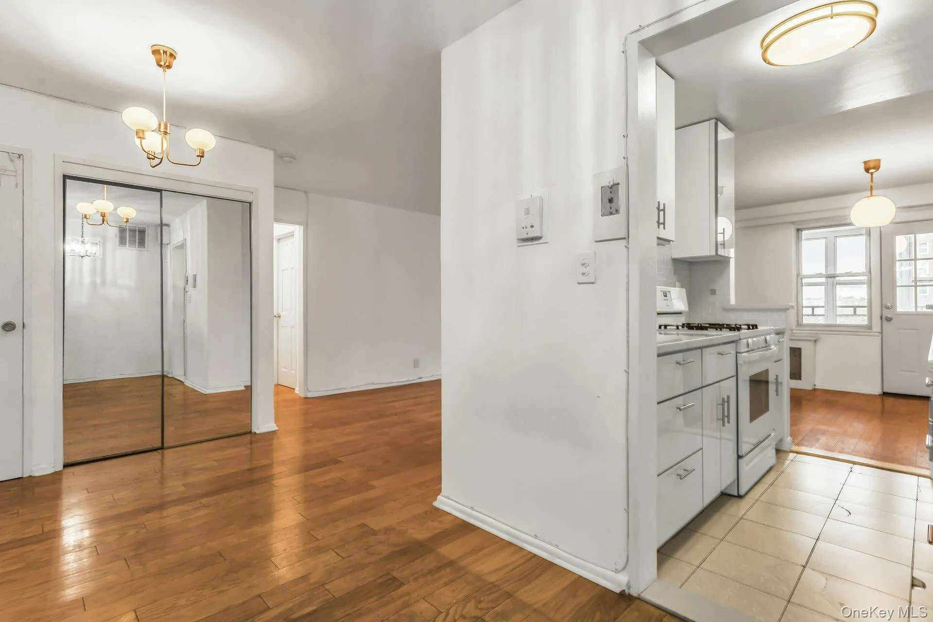 Kitchen with hanging light fixtures, white cabinets, white gas stove, and light wood-style flooring Kitchen with hanging light fixtures, white cabinets, white gas stove, and light wood-style flooring