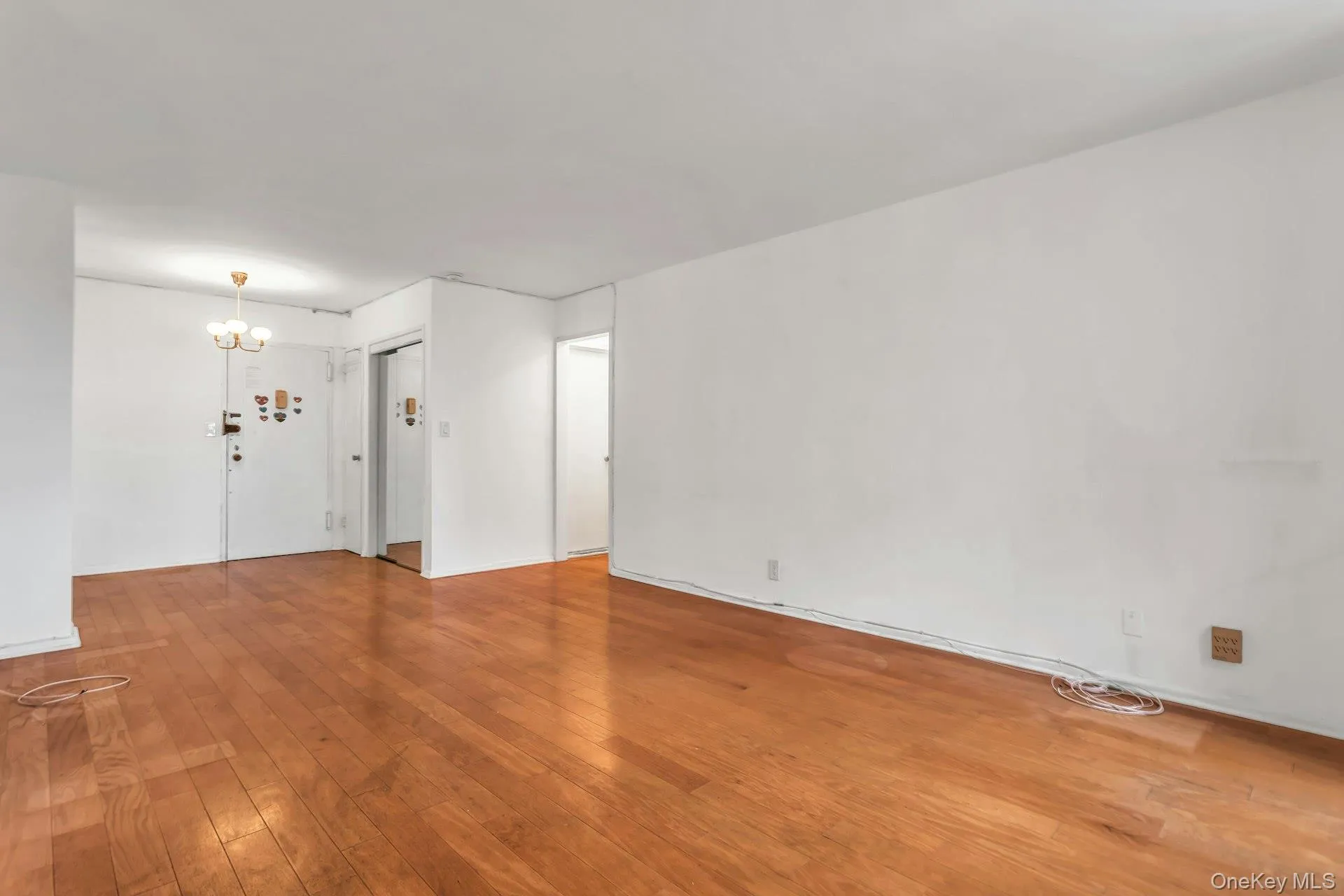 Spare room featuring wood-type flooring and a chandelier Spare room featuring wood-type flooring and a chandelier