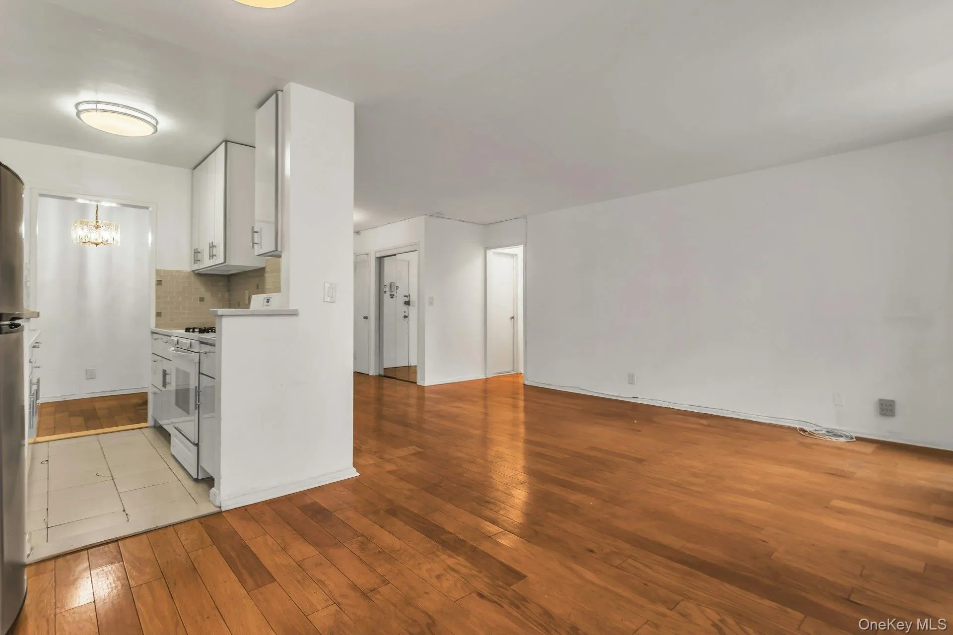 Kitchen featuring white cabinets, light wood-type flooring, light countertops, white gas range oven, and backsplash Kitchen featuring white cabinets, light wood-type flooring, light countertops, white gas range oven, and backsplash