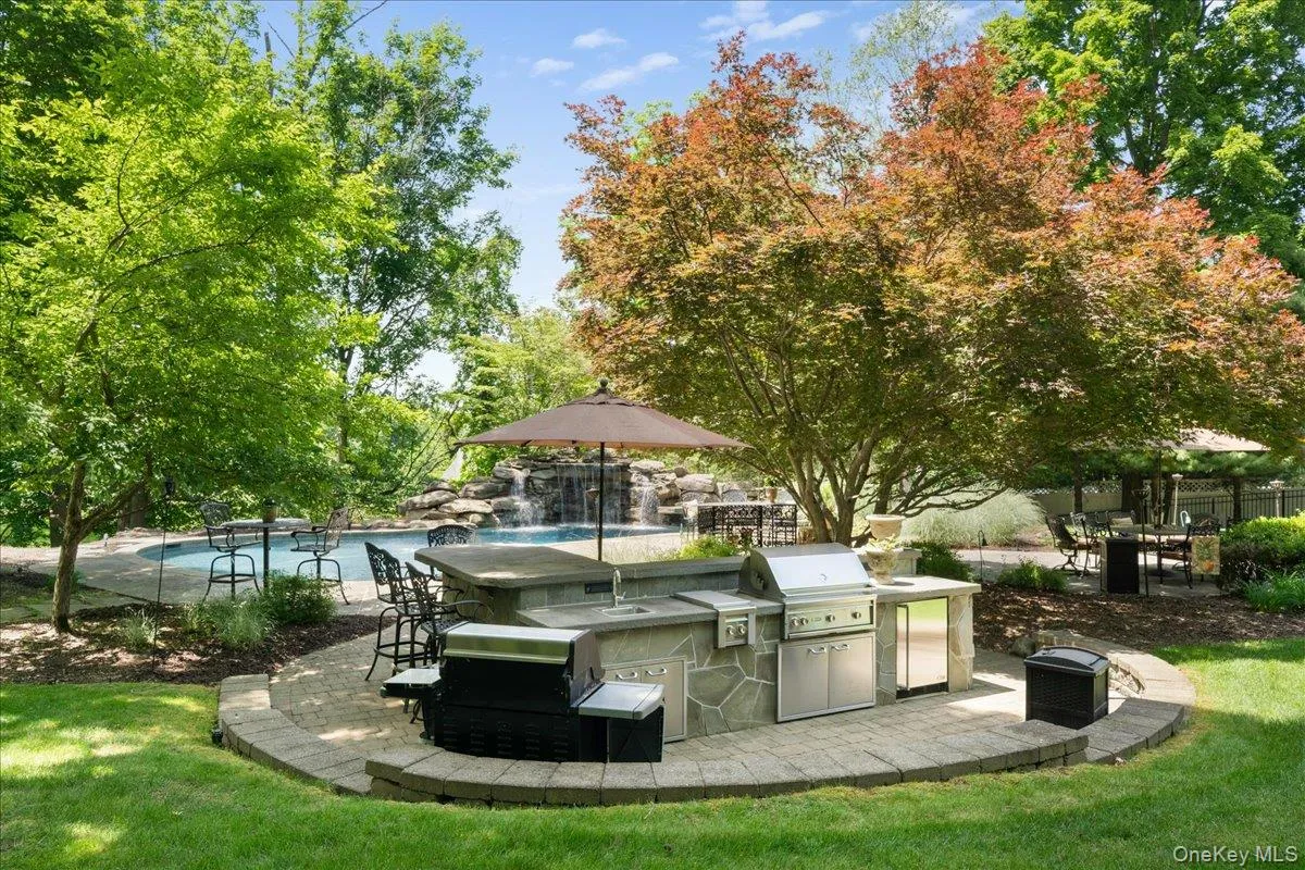 Outdoor kitchen featuring a built-in BBQ grill, cooktop, and refrigerator—perfect for effortless outdoor entertaining. Outdoor kitchen featuring a built-in BBQ grill, cooktop, and refrigerator—perfect for effortless outdoor entertaining.