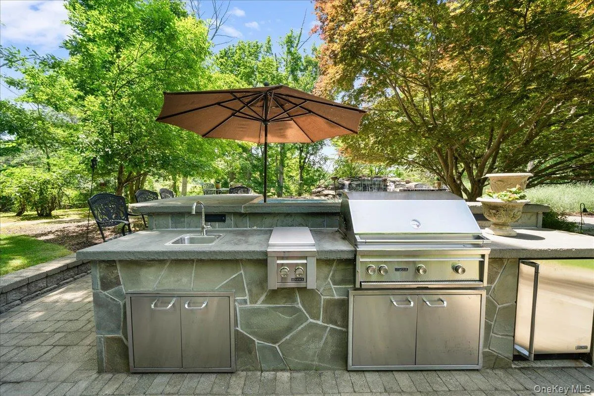 Outdoor kitchen featuring a built-in BBQ grill, cooktop, and refrigerator—perfect for effortless outdoor entertaining. Outdoor kitchen featuring a built-in BBQ grill, cooktop, and refrigerator—perfect for effortless outdoor entertaining.
