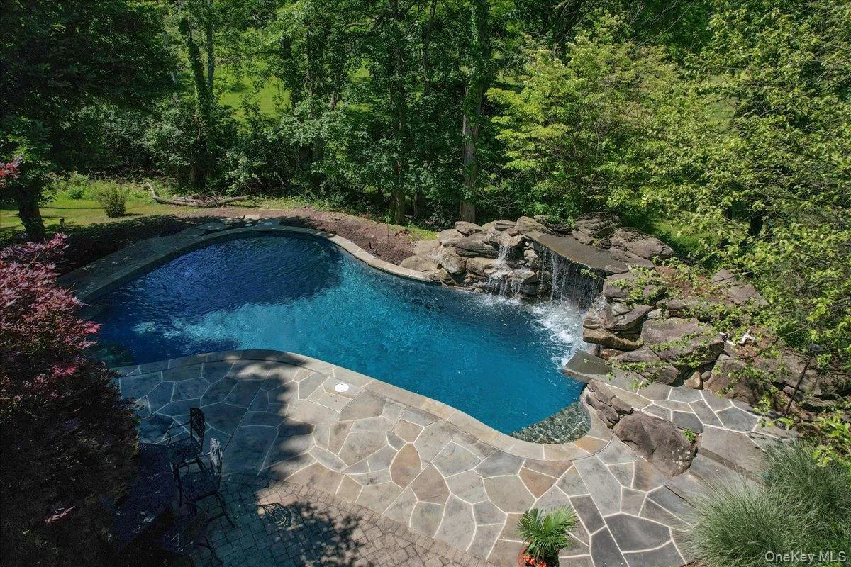 Step off the deck and follow the path to your private backyard oasis, featuring a stunning in-ground pool, stone hardscaping, mature landscaping, and a resort-style waterfall cascading over a natural grotto and dramatic rock ledge. Step off the deck and follow the path to your private backyard oasis, featuring a stunning in-ground pool, stone hardscaping, mature landscaping, and a resort-style waterfall cascading over a natural grotto and dramatic rock ledge.