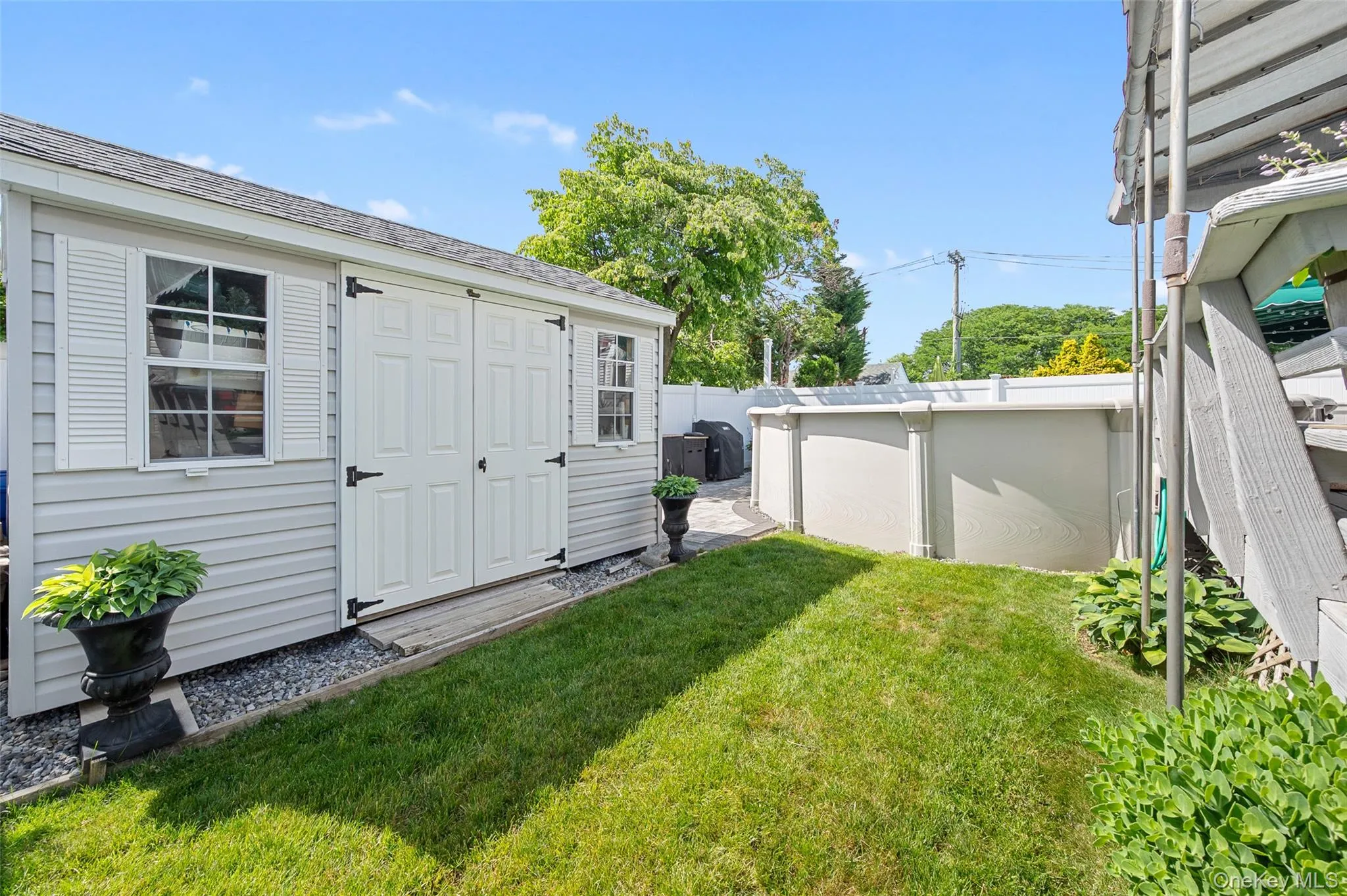 Backyard featuring a shed with double doors, white shutters, and an above-ground pool Backyard featuring a shed with double doors, white shutters, and an above-ground pool