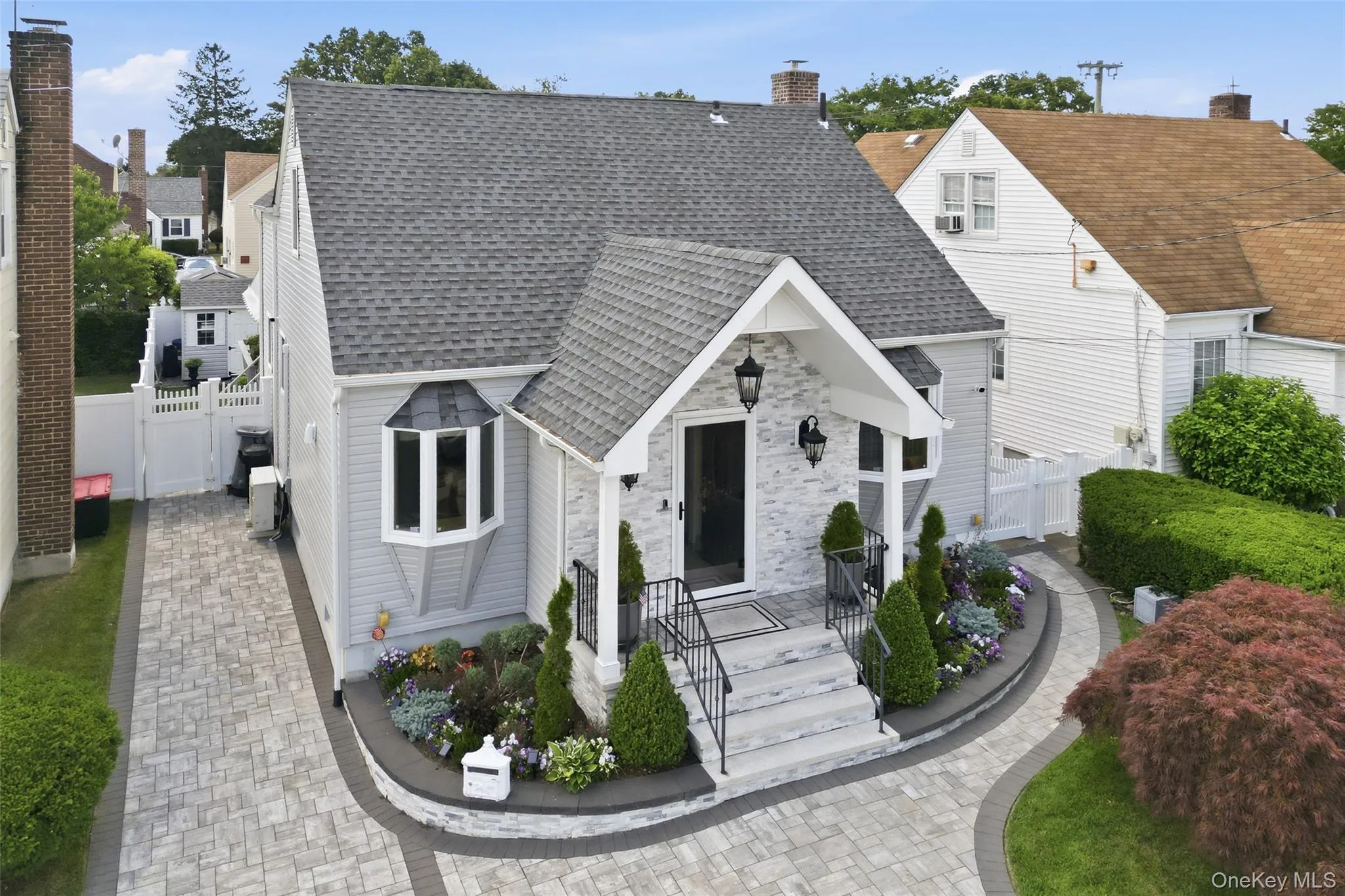 Curb appeal featuring a newly paved driveway and walkway, a covered entry with stone facade, a bay window, and mature landscaping Curb appeal featuring a newly paved driveway and walkway, a covered entry with stone facade, a bay window, and mature landscaping