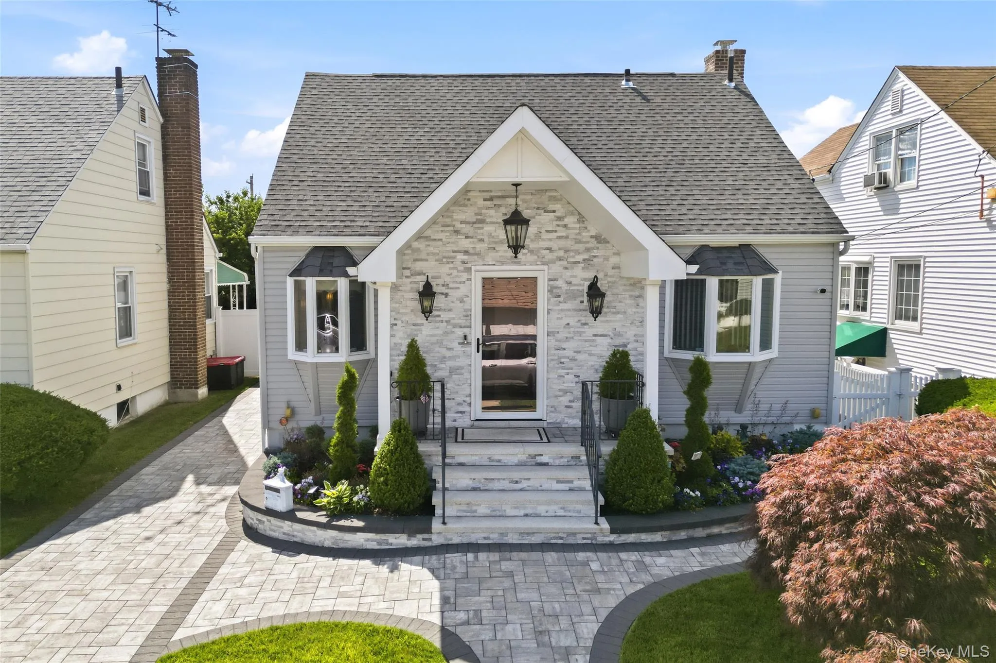 Charming residence featuring a stone veneer facade, a gabled entry, and two bay windows Charming residence featuring a stone veneer facade, a gabled entry, and two bay windows