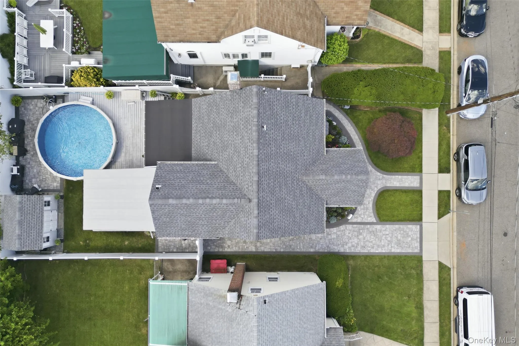Property featuring a shingled main roof, a paved front driveway, an expansive rear deck, and a circular above-ground pool Property featuring a shingled main roof, a paved front driveway, an expansive rear deck, and a circular above-ground pool