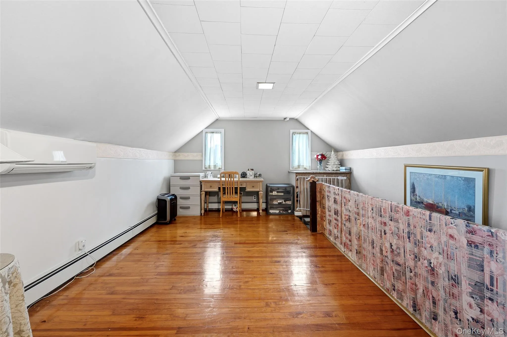 Attic space featuring wood-finish flooring, sloped ceilings, and built-in window framing Attic space featuring wood-finish flooring, sloped ceilings, and built-in window framing