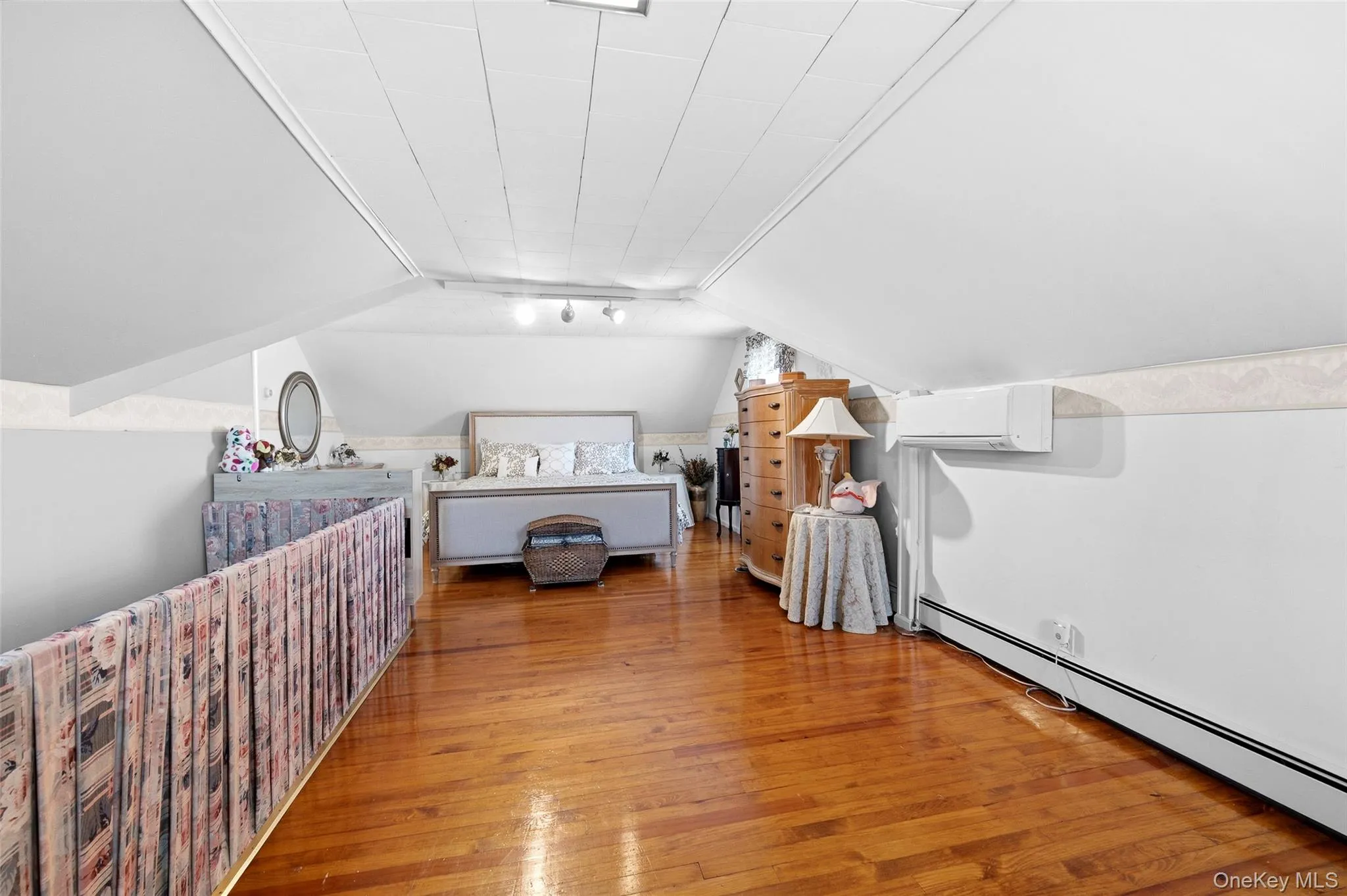 Wood-finish flooring complemented by white walls and a sloped ceiling Wood-finish flooring complemented by white walls and a sloped ceiling