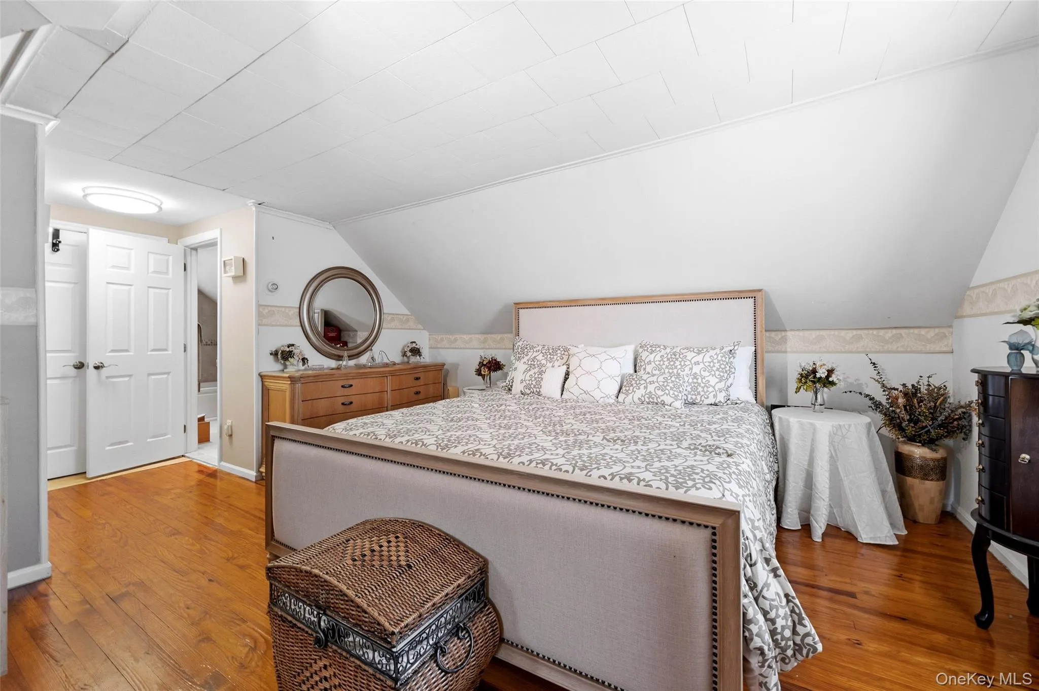 Hardwood flooring accents this room featuring an angled ceiling and neutral wall tones Hardwood flooring accents this room featuring an angled ceiling and neutral wall tones