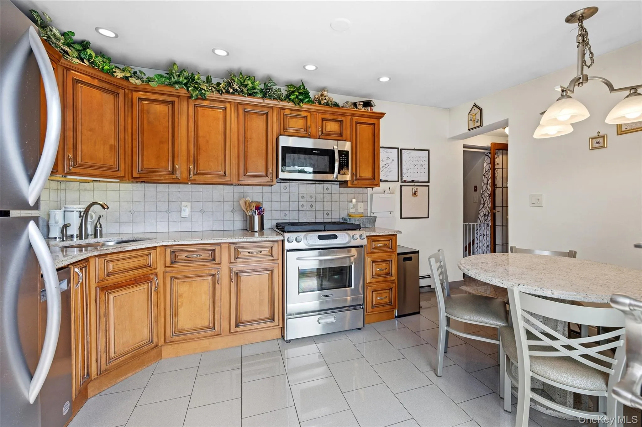 Kitchen featuring wood cabinetry, stainless steel appliances, and a tiled backsplash Kitchen featuring wood cabinetry, stainless steel appliances, and a tiled backsplash