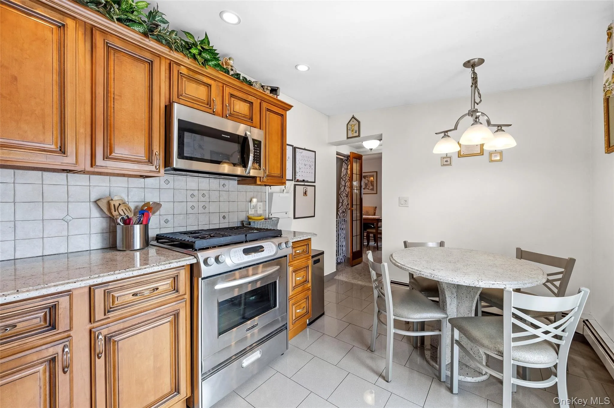 Kitchen featuring wood cabinetry, stainless steel appliances including a microwave and range, light-toned countertops, and a tiled backsplash Kitchen featuring wood cabinetry, stainless steel appliances including a microwave and range, light-toned countertops, and a tiled backsplash