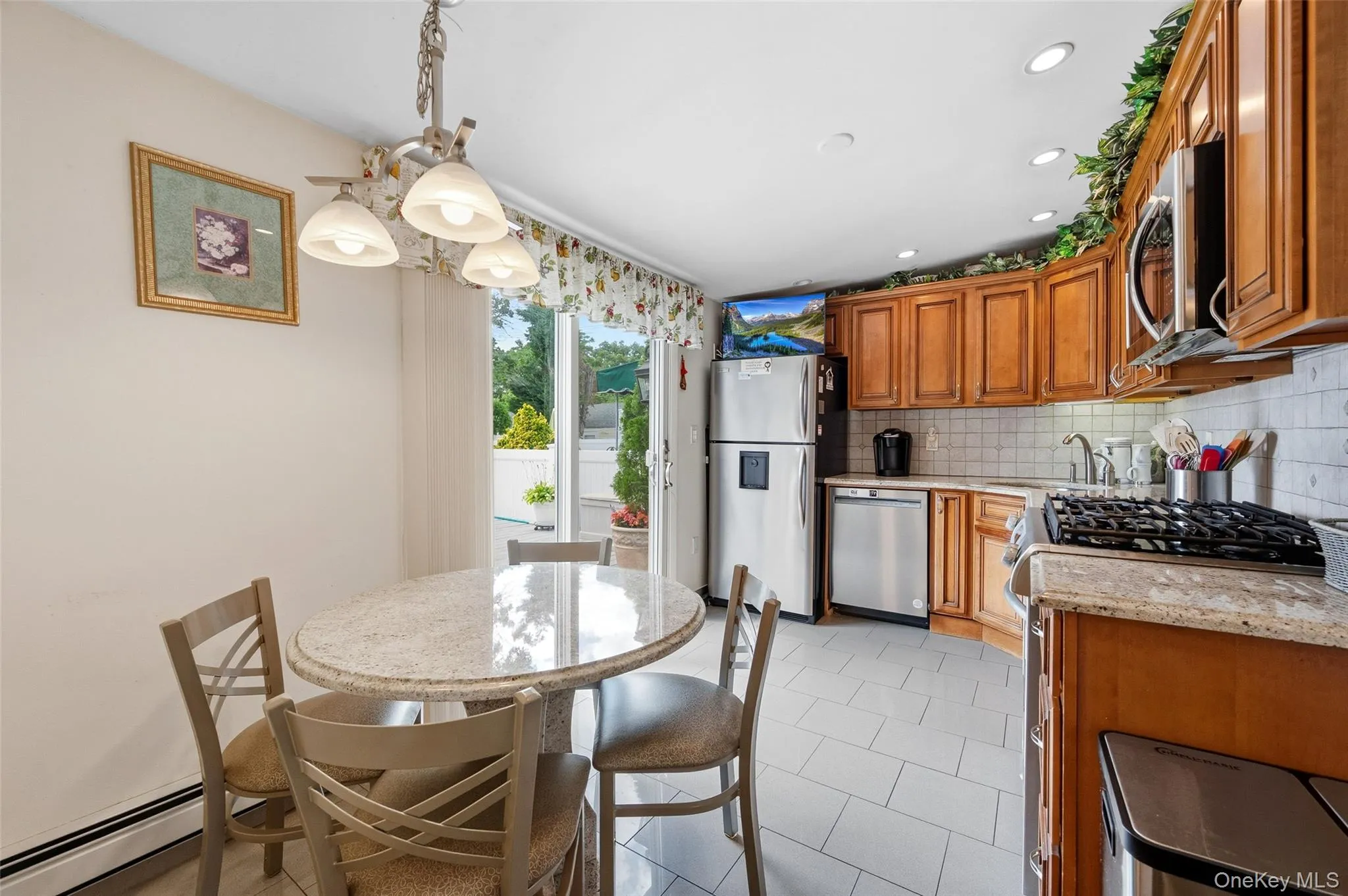Kitchen with wood cabinetry, stainless steel appliances, and light-toned tile flooring Kitchen with wood cabinetry, stainless steel appliances, and light-toned tile flooring