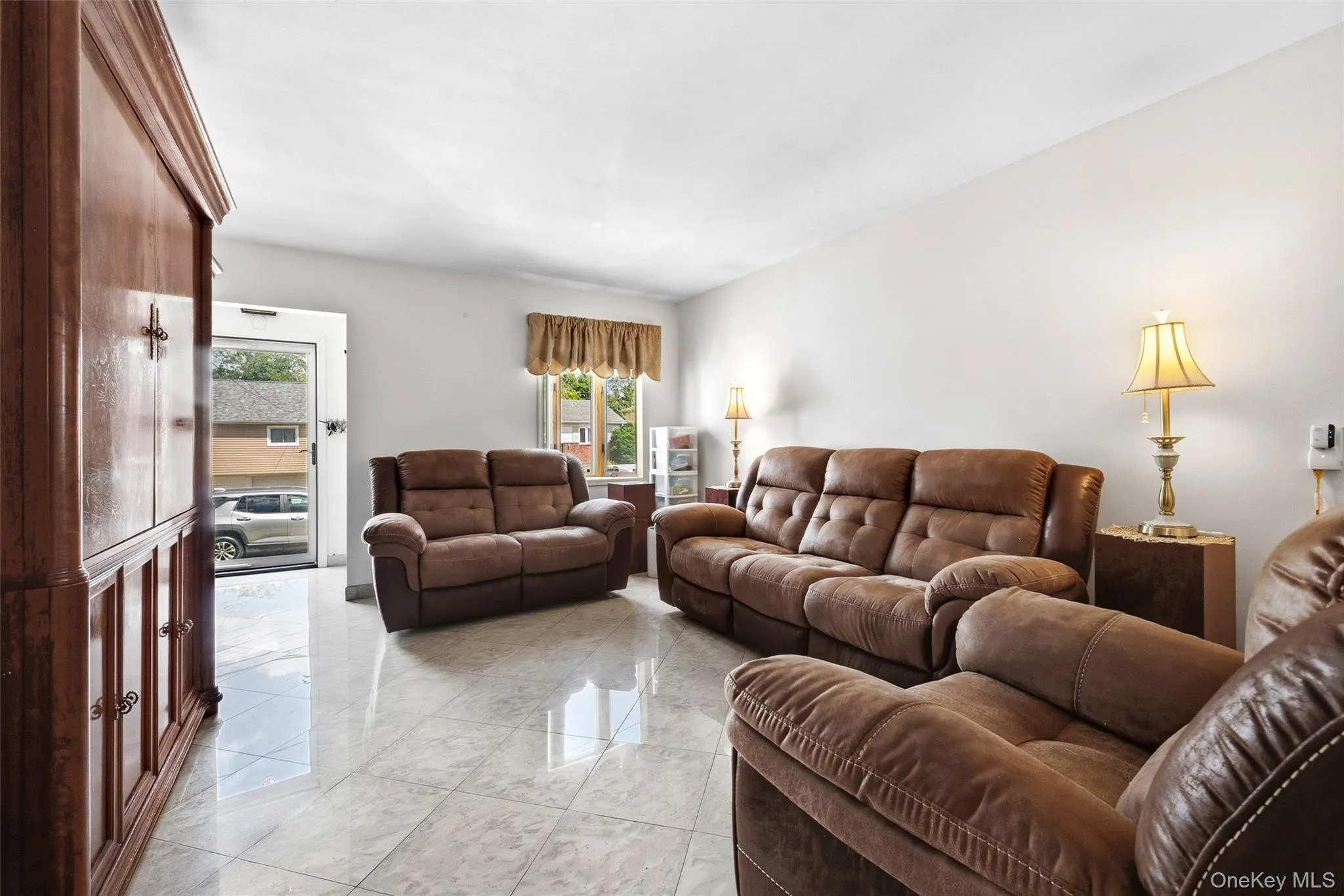 Living area featuring light-toned flooring, white walls, and a glass-paneled entry door Living area featuring light-toned flooring, white walls, and a glass-paneled entry door
