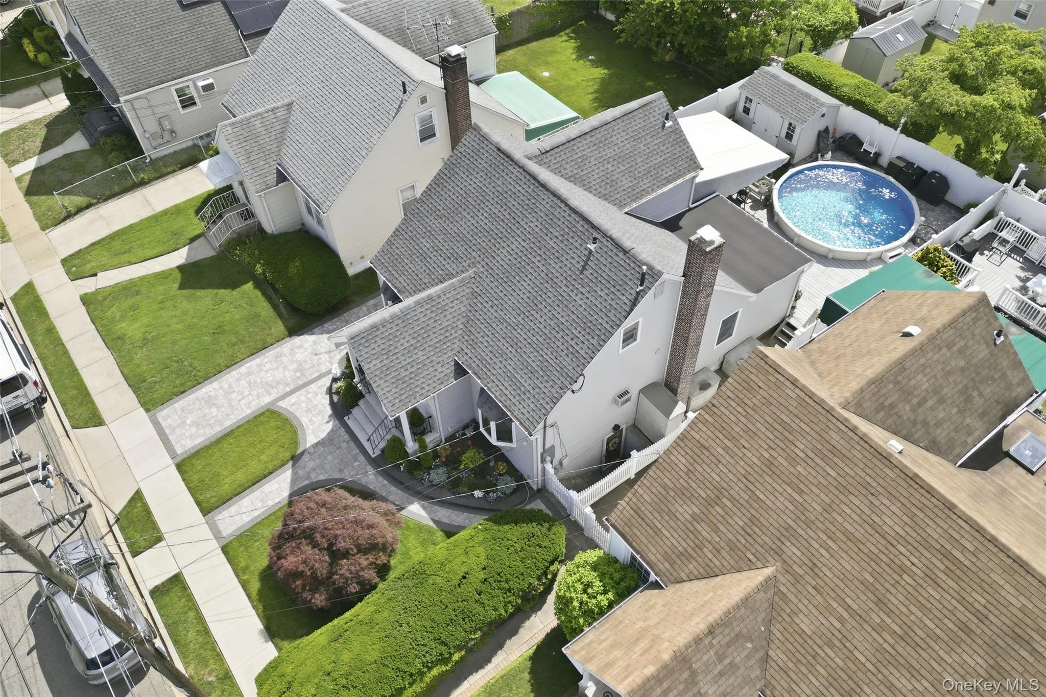 Property featuring a grey shingle roof, light-colored siding, a paved driveway, and a fenced backyard with an above-ground pool Property featuring a grey shingle roof, light-colored siding, a paved driveway, and a fenced backyard with an above-ground pool