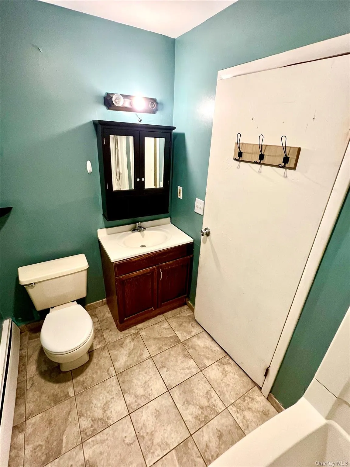 Bathroom featuring vanity, a baseboard radiator, and light tile patterned floors Bathroom featuring vanity, a baseboard radiator, and light tile patterned floors