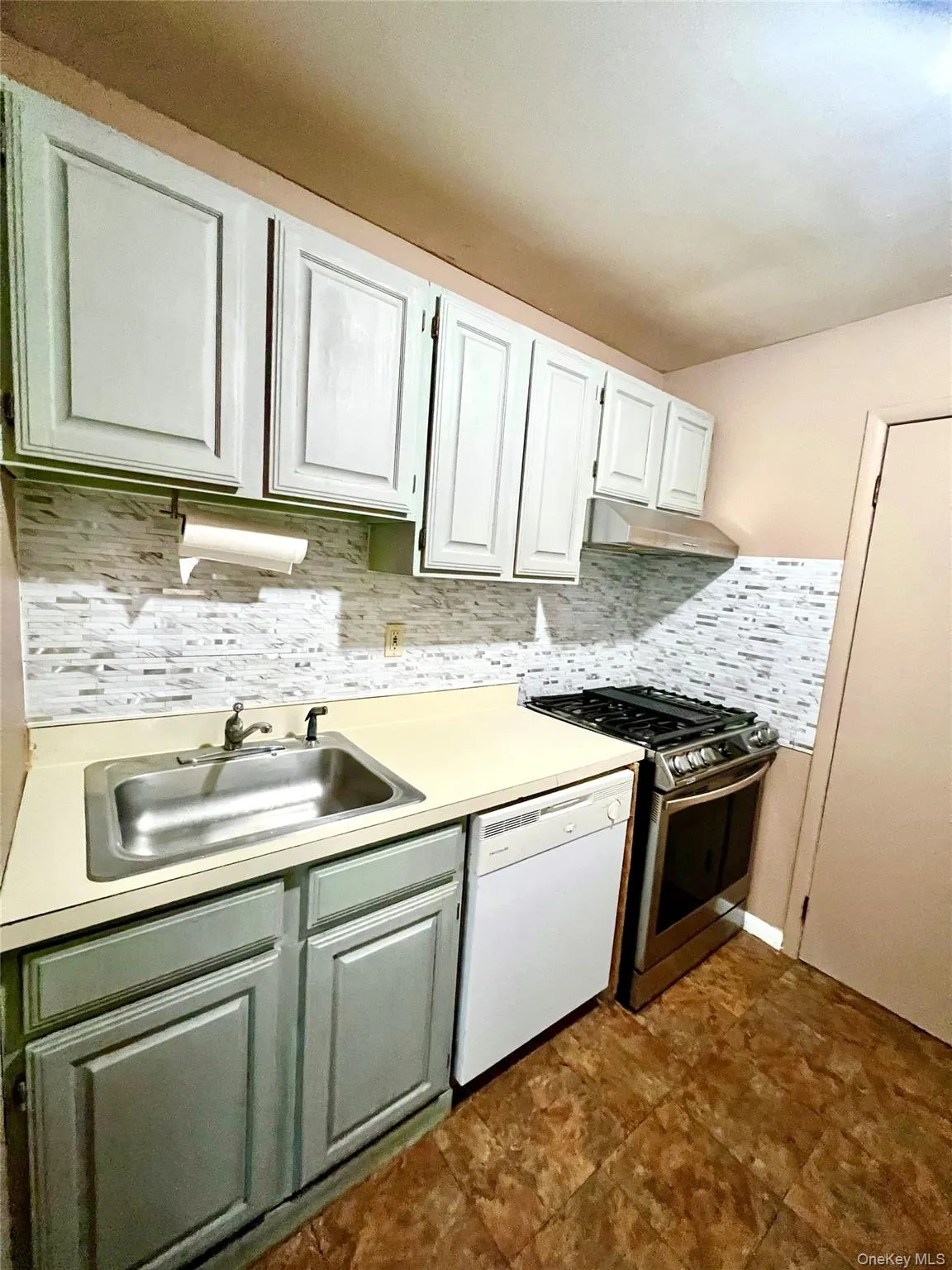 Kitchen with tasteful backsplash, light countertops, stainless steel gas range oven, and dishwasher Kitchen with tasteful backsplash, light countertops, stainless steel gas range oven, and dishwasher