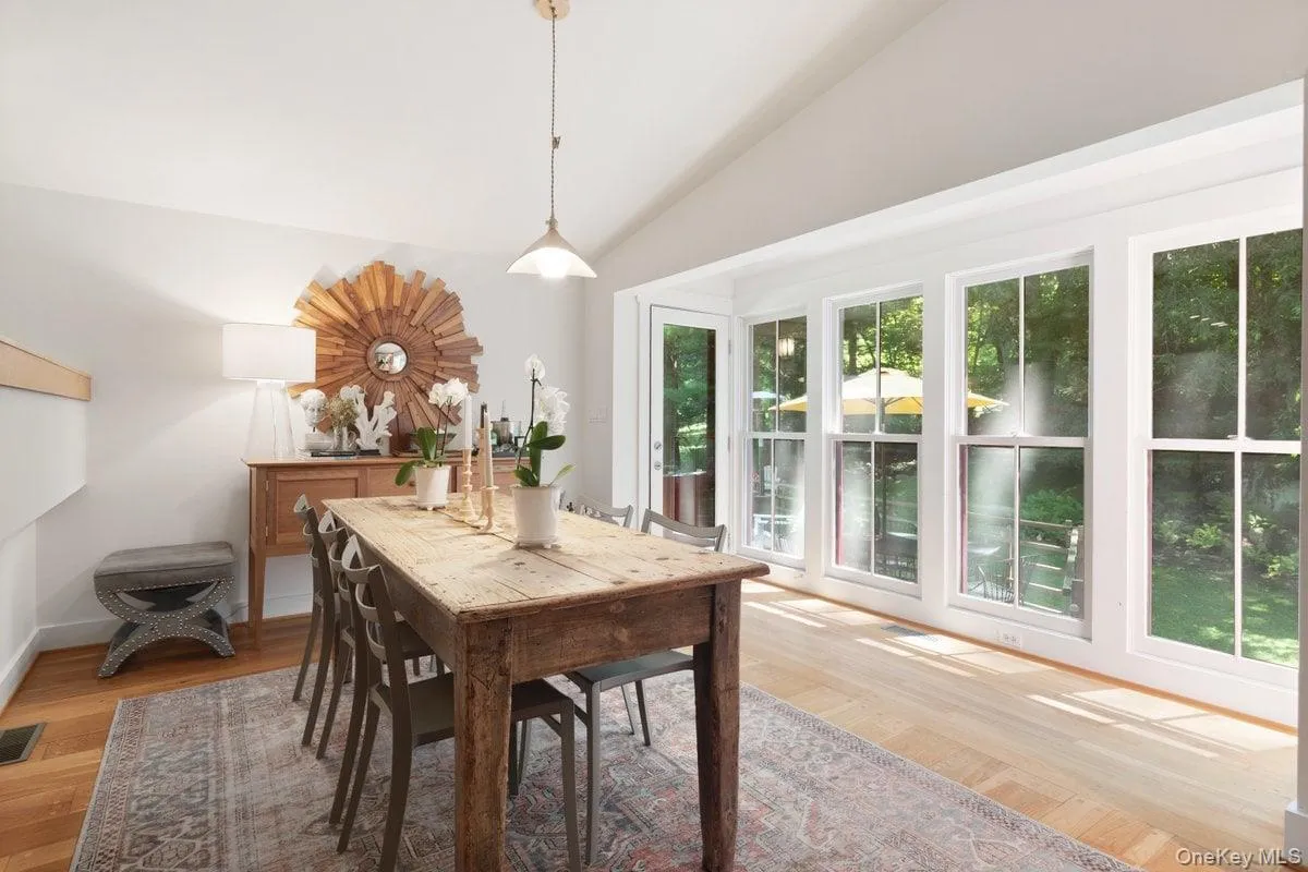 A wall of windows anchors the dining room, filling the space with natural sunlight and offering serene backyard views. A glass door provides access to the deck, making indoor-outdoor living effortless. A wall of windows anchors the dining room, filling the space with natural sunlight and offering serene backyard views. A glass door provides access to the deck, making indoor-outdoor living effortless.