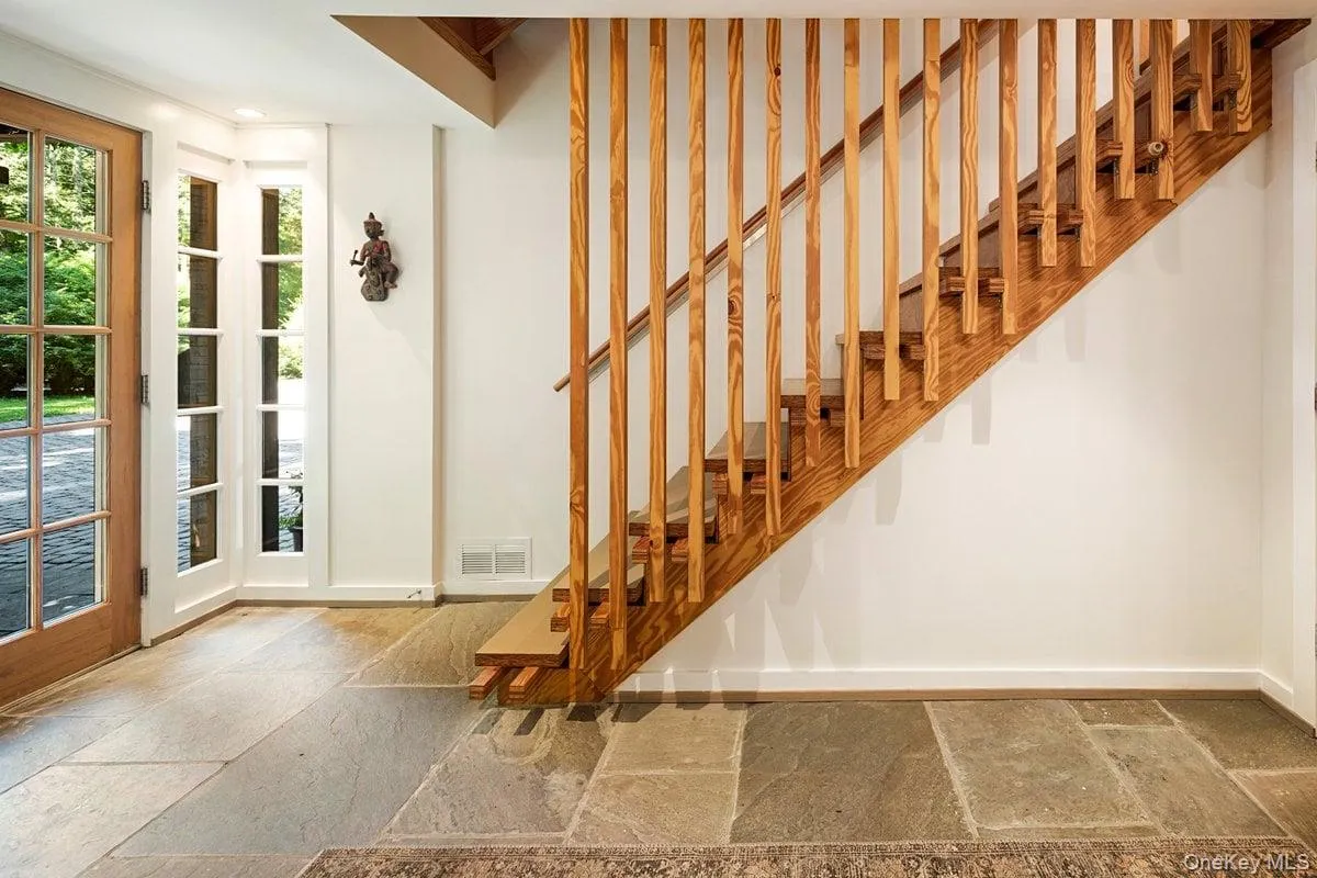 Step into the stone-tiled foyer, through the glass front door where a beautiful wooden staircase welcomes you and leads you up to the main level.. Step into the stone-tiled foyer, through the glass front door where a beautiful wooden staircase welcomes you and leads you up to the main level..