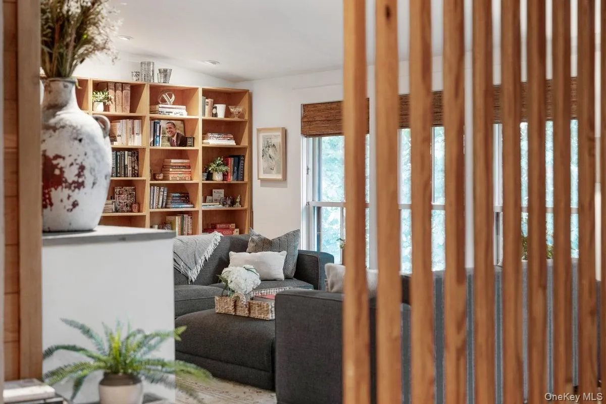 A peek into the living room through the distinctive wood slat wall as you ascend the stairs from the entry level. A peek into the living room through the distinctive wood slat wall as you ascend the stairs from the entry level.