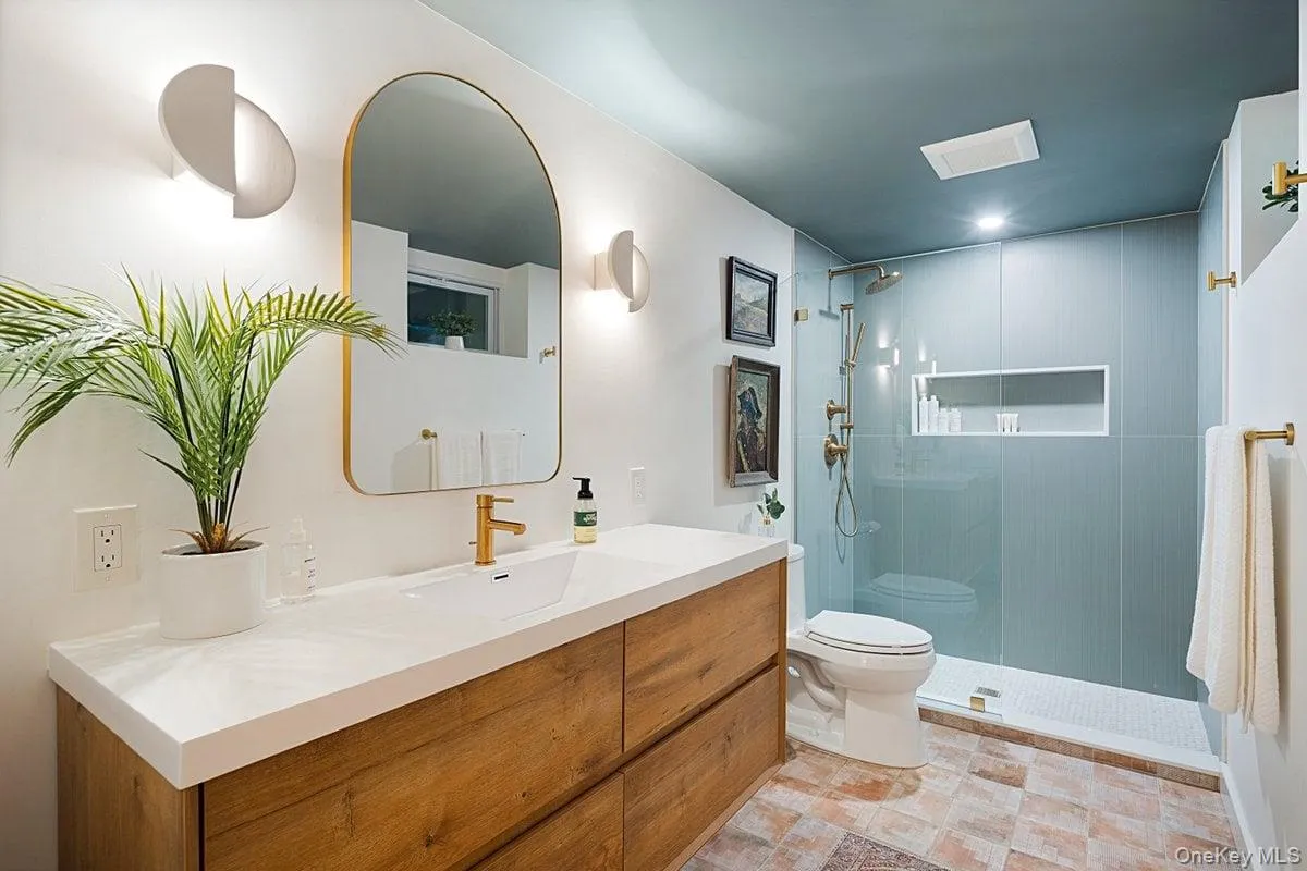 A new spa-style bathroom off the main-level bonus room boasts a sleek seamless glass shower, stylish glass tiles, and a floating vanity topped with a granite countertop. A new spa-style bathroom off the main-level bonus room boasts a sleek seamless glass shower, stylish glass tiles, and a floating vanity topped with a granite countertop.