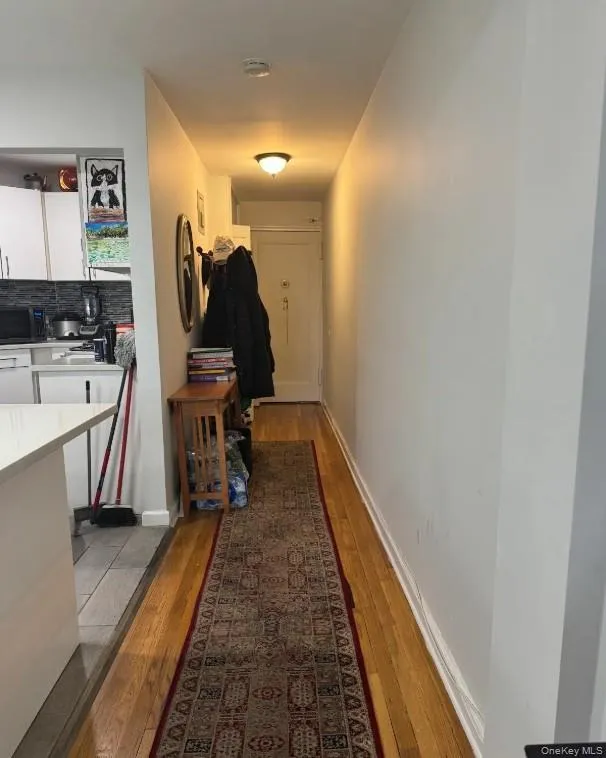 Corridor featuring light wood-style flooring and baseboards Corridor featuring light wood-style flooring and baseboards
