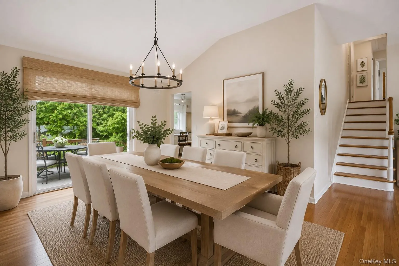 Vaulted ceiling with a chandelier, wood-finish flooring, sliding glass door to an outdoor patio, and a staircase with wood treads Vaulted ceiling with a chandelier, wood-finish flooring, sliding glass door to an outdoor patio, and a staircase with wood treads