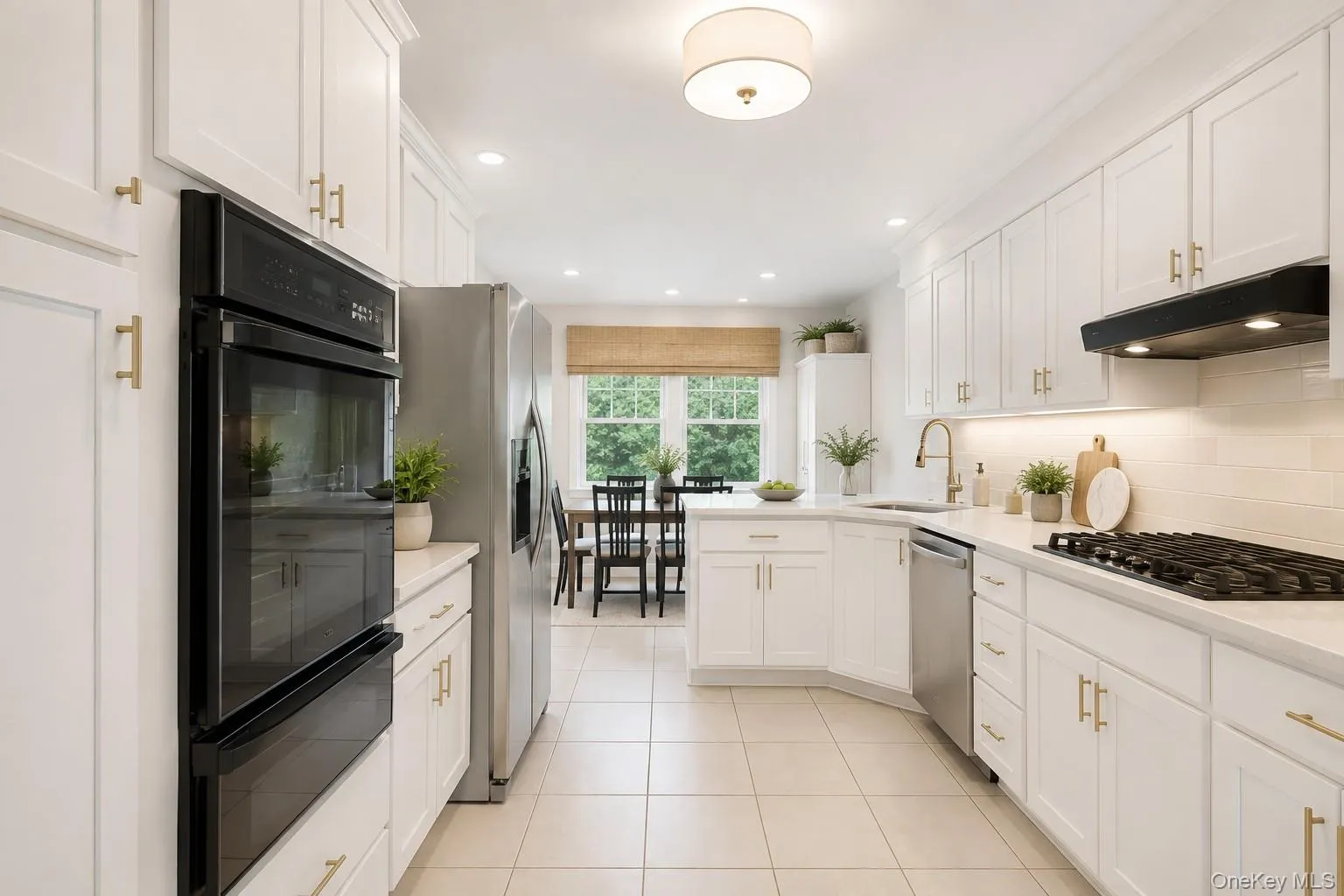 White cabinetry with gold-tone hardware, stainless steel appliances including a double oven and refrigerator, light-toned tile flooring, and a stone-finish countertop White cabinetry with gold-tone hardware, stainless steel appliances including a double oven and refrigerator, light-toned tile flooring, and a stone-finish countertop