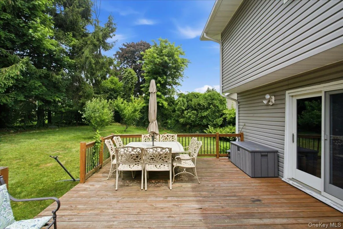 Spacious wood-finish deck bordered by a wooden railing overlooking a lush green lawn and mature trees Spacious wood-finish deck bordered by a wooden railing overlooking a lush green lawn and mature trees