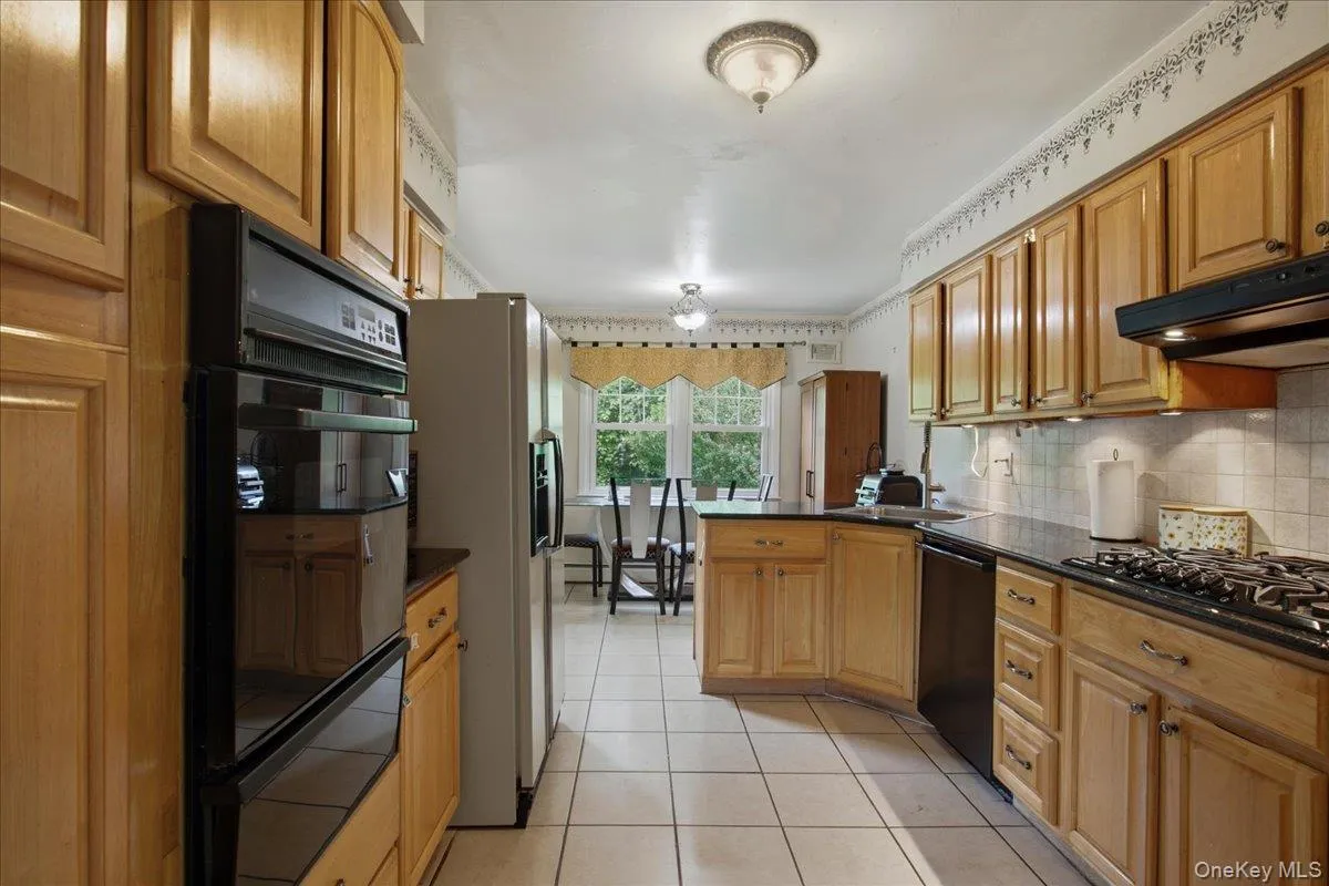 Kitchen featuring wood cabinetry, dark countertops, a built-in double oven, a gas cooktop, and tile flooring Kitchen featuring wood cabinetry, dark countertops, a built-in double oven, a gas cooktop, and tile flooring