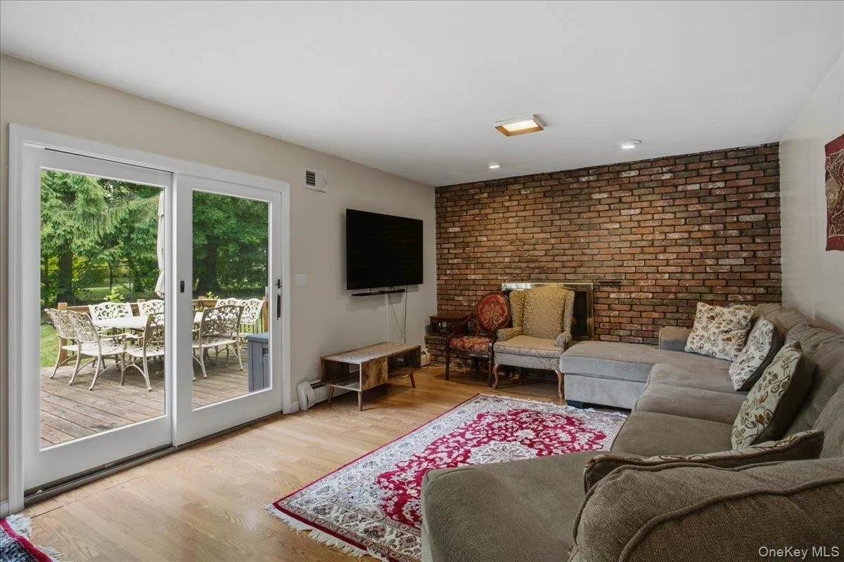 Living area featuring hardwood flooring, a brick accent wall, recessed lighting, and a sliding glass door providing access to an outdoor deck Living area featuring hardwood flooring, a brick accent wall, recessed lighting, and a sliding glass door providing access to an outdoor deck