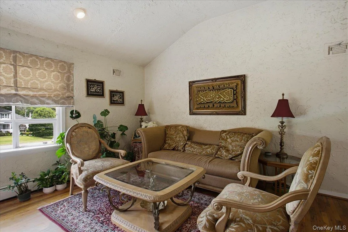 Living area featuring vaulted ceilings, textured wall finishes, and wood-finish flooring Living area featuring vaulted ceilings, textured wall finishes, and wood-finish flooring