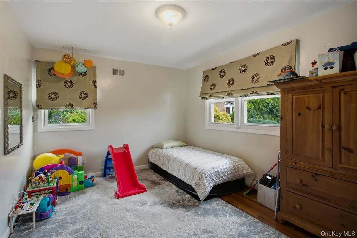 Bedroom on first floor featuring light beige wall paint, white trim, and a combination of wood-finish flooring and area rug Bedroom on first floor featuring light beige wall paint, white trim, and a combination of wood-finish flooring and area rug