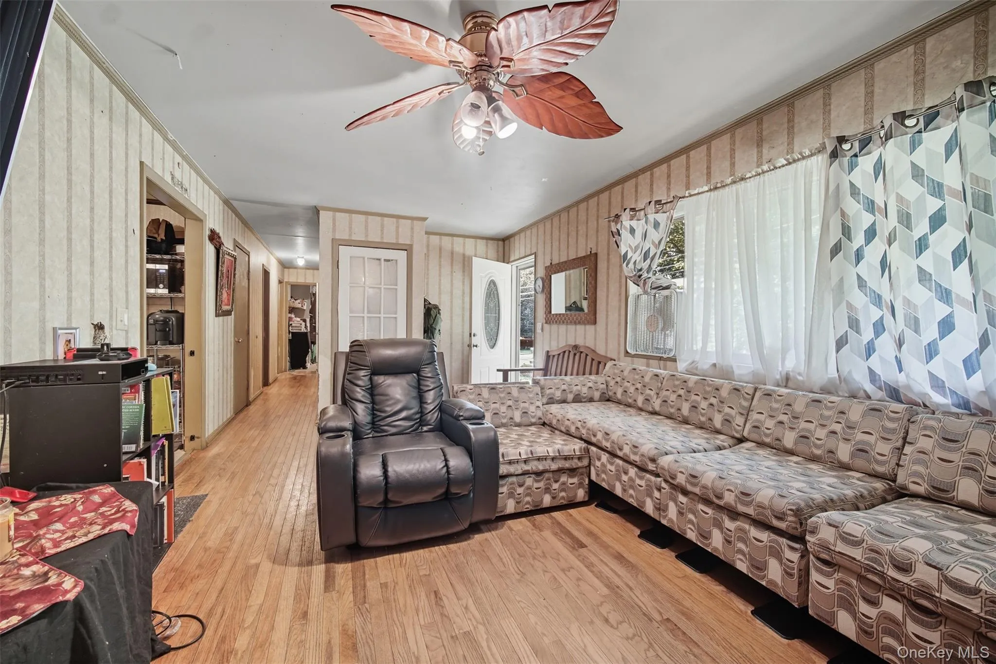 Living room featuring light wood-type flooring, crown molding, and a ceiling fan Living room featuring light wood-type flooring, crown molding, and a ceiling fan