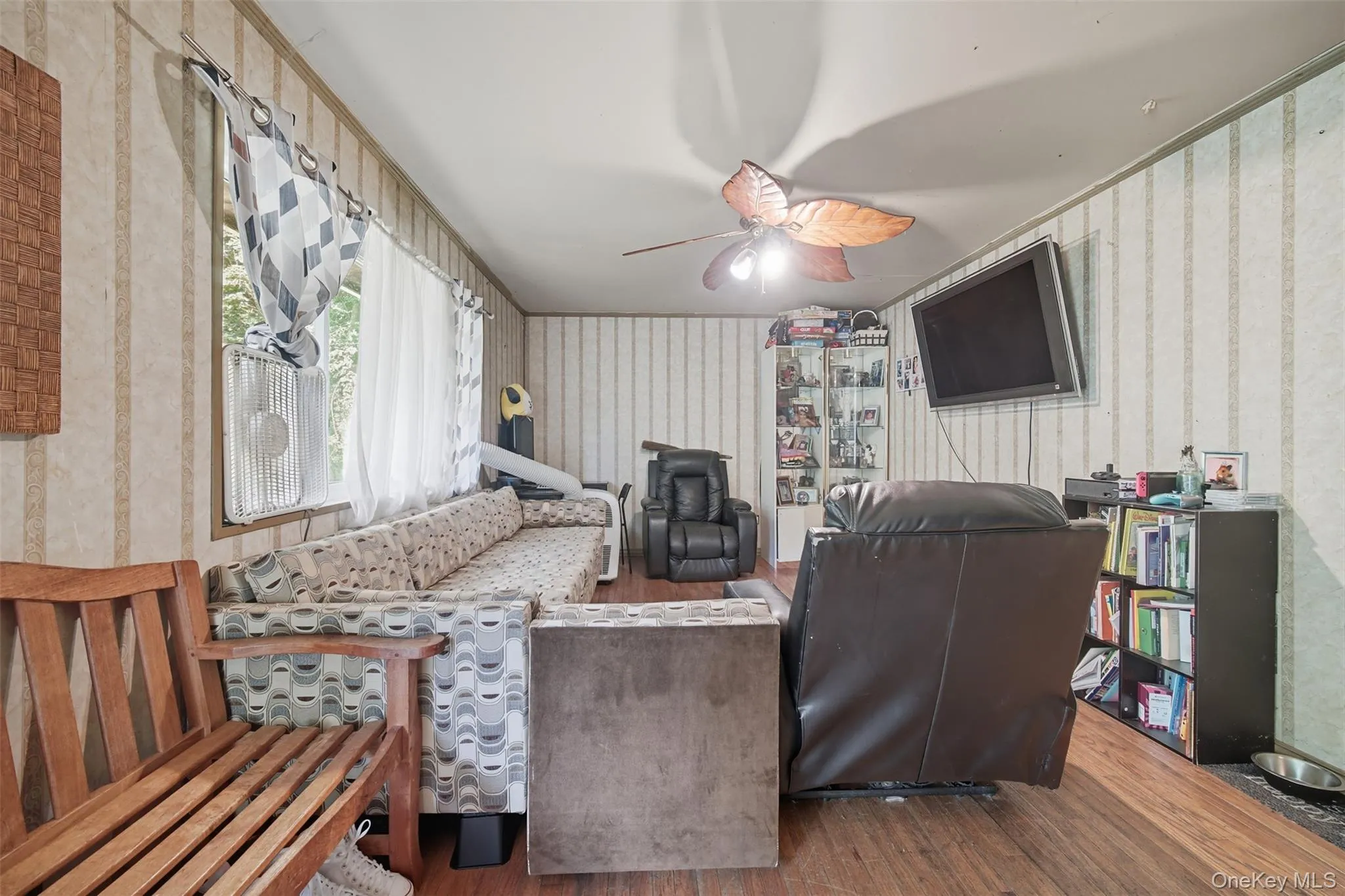 Living area with wood finished floors, wallpapered walls, and ceiling fan Living area with wood finished floors, wallpapered walls, and ceiling fan
