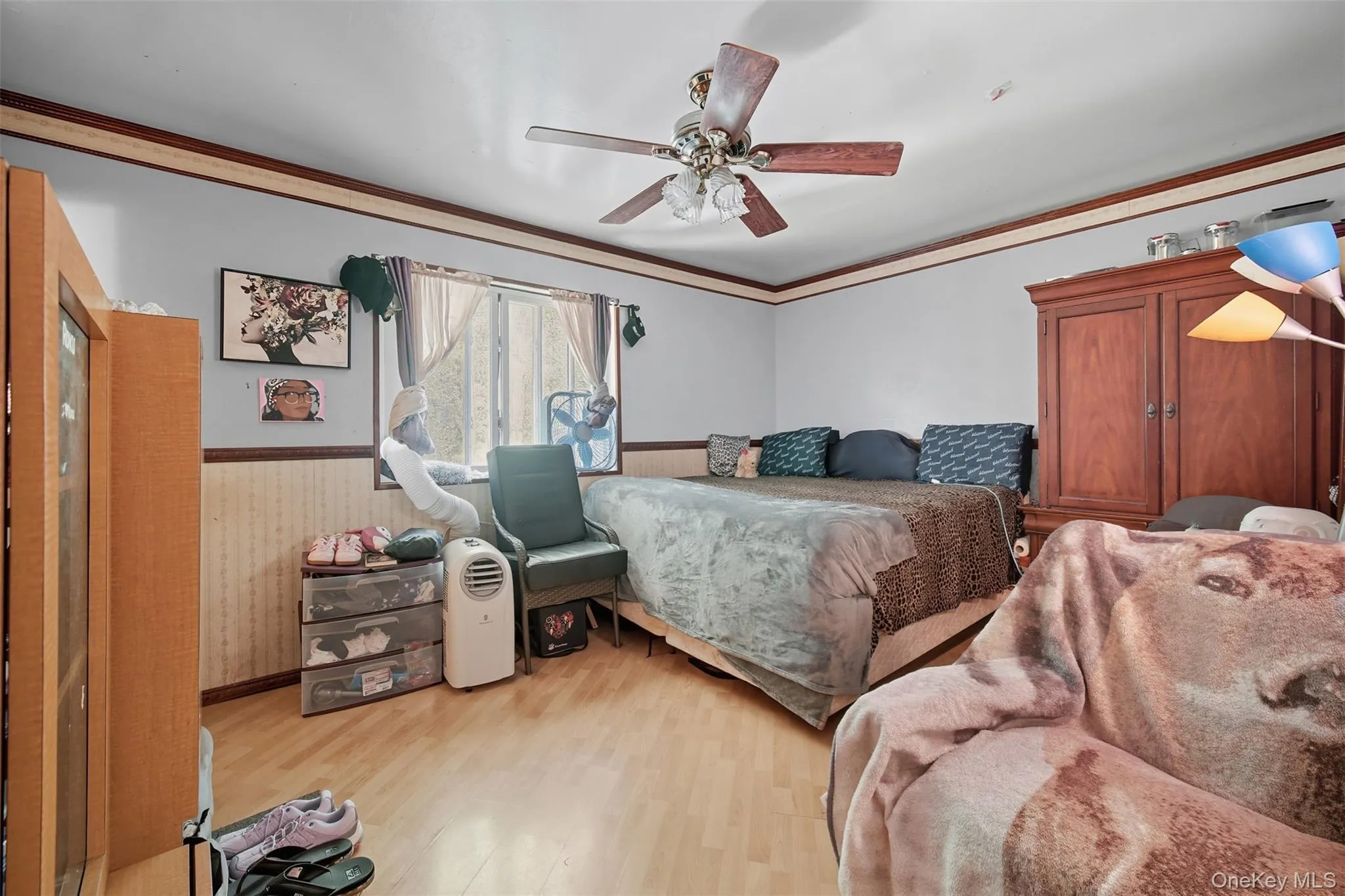 Bedroom featuring ornamental molding, light wood-style flooring, a ceiling fan, and wainscoting Bedroom featuring ornamental molding, light wood-style flooring, a ceiling fan, and wainscoting