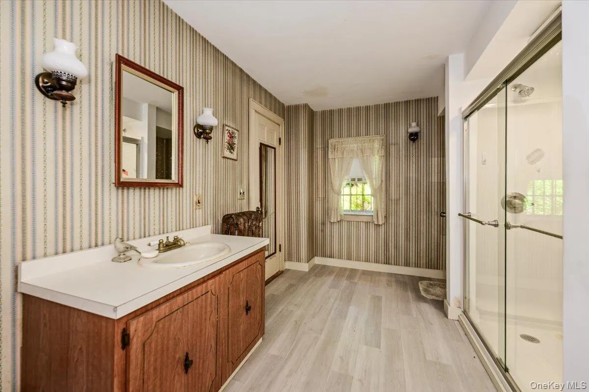 Bathroom with wood vanity and shower with glass sliding door. Bathroom with wood vanity and shower with glass sliding door.