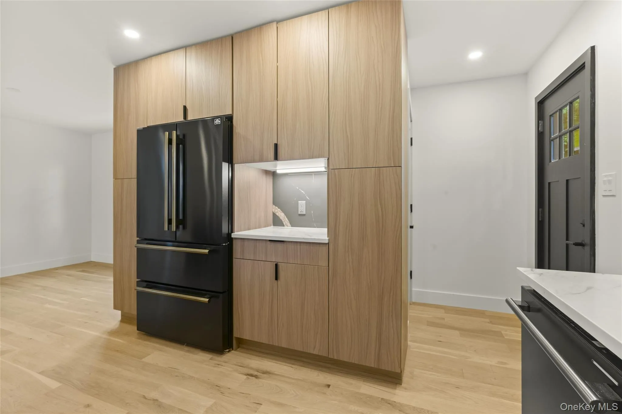 Integrated kitchen cabinetry featuring wood-finish panels and a built-in black refrigerator Integrated kitchen cabinetry featuring wood-finish panels and a built-in black refrigerator